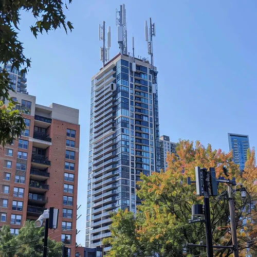 Tall residential building with multiple cellular antennas mounted on top of tower